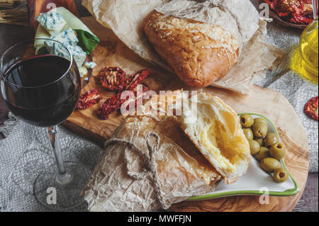 Ein Glas trockener Rotwein und Italienische Focaccia Brot mit Käse und eine Käseplatte mit Feigen und Gorgonzola, Brie, DorBlu und Trauben. Selektiver Fokus Stockfoto