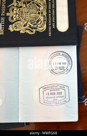 Brisbane Ankunft und Abreise Briefmarken in einer australischen Reisepass, ruht auf alten blauen britischen Pässen Stockfoto