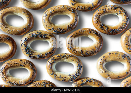 Ein Foto von Bagels mit Mohn. Bagels arrangiert als Muster. Isoliert Foto auf dem weißen Hintergrund für Site über Küche, Lebensmittel, Traditionen. Stockfoto