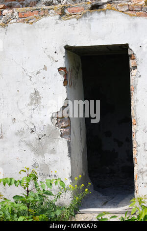 Eingang zum alten zerstörten Gebäude. Loch von einer Kugel in die Wand einer verlassenen Burg. Stockfoto