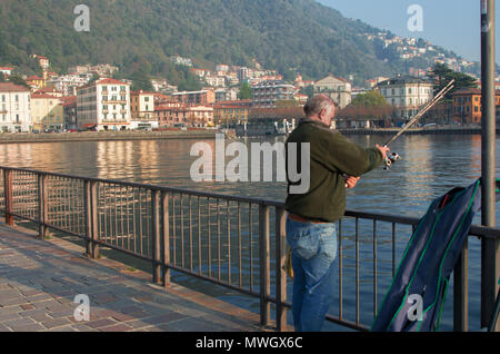 Im Ruhestand verbringt er seine freie Zeit angeln am Comer See von einem Pier in der Stadt Stockfoto