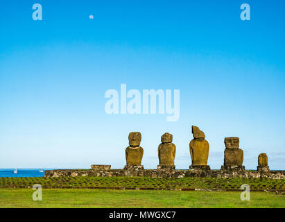 Ahu Tahai Moai Vai Ure, Figuren, Hanga Roa, Easter Island, Chile, mit Mond im blauen Himmel bei Tag und verankert Yachten im Pazifischen Ozean Stockfoto