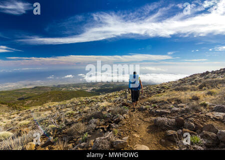 Mann mit Rucksack auf dem Weg in der Nähe von semidesert neide Vulkan auf der Insel Teneriffa mit Steinen und blauer Himmel und Wolken unter Stockfoto