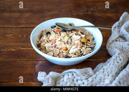 Eine Schüssel voll mit Müsli Müsli mit Löffel über eine hölzerne Tabelle Stockfoto