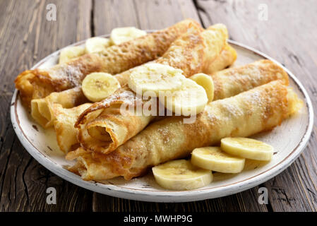 Leckere crepes Rolle mit bananenscheiben auf hölzernen Tisch. Nähe zu sehen. Stockfoto