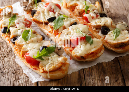 Italienische Sandwiches, Pizza, Auflauf: Schneiden baguette gebacken mit Hähnchen, Käse, Tomaten, Oliven und Champignons close-up auf dem Tisch. Horizontale Stockfoto