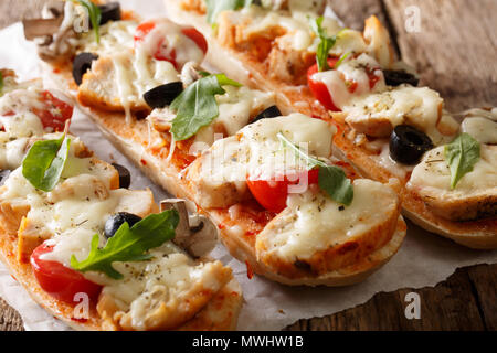 Selbstgemachtes Sandwich Pizza baguette gebacken mit Hähnchen, Käse, Tomaten, Oliven und Champignons close-up auf dem Tisch. Horizontale Stockfoto