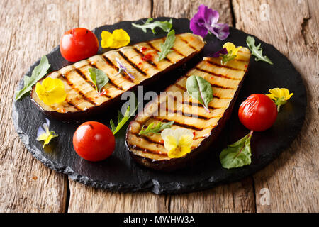 Schöne Gegrillte Aubergine mit Tomate, Kräuter und essbare Blüten in der Nähe serviert - auf den Tisch. Horizontale Stockfoto