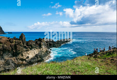 Touristen auf einer Klippe mit Blick auf die Klippen und felsigen Küste mit Erodierten lava Vulkangestein, Ana Kai Tangata, Hanga Roa, Rapa Nui, Easter Island, Chile Stockfoto