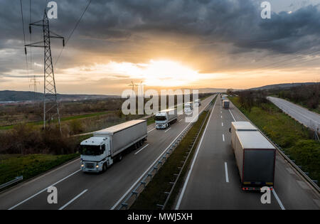 Wohnwagen oder LKW-Konvoi der weißen Linie auf ein Land Autobahn bei Sonnenuntergang Stockfoto