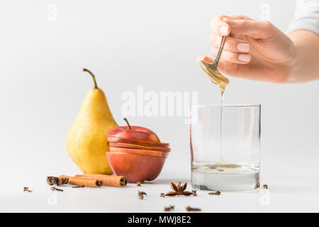 7/8 Schuß von Frau gießen Honig im Glas vom Löffel am weißen Tisch Stockfoto