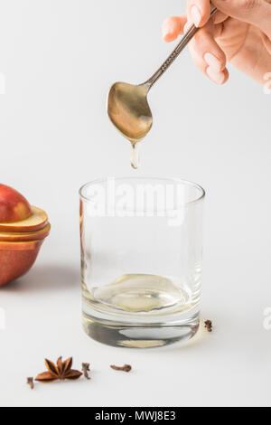 7/8 Schuß von Frau gießen Honig im Glas vom Löffel am weißen Tisch Stockfoto