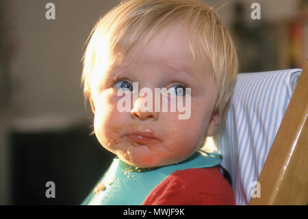 Unordentliche 9 Monate alten Baby Boy mit Essen rund um den Mund Stockfoto