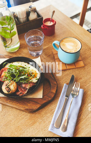 Frühstück mit Spiegelei in der Pfanne und Kaffee serviert. Stockfoto