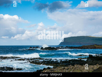 Ocean Waves auf felsigen Ufer brechen, South Coast auf der Osterinsel, Rapa Nui, Chile, mit Blick auf den erloschenen Vulkan Rano Kau Stockfoto