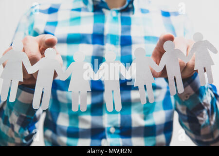 Auswahl der Kandidaten für die Arbeit, für die Rekrutierung. Der Mann seine Finger an den Figuren aus Papier Ausschneiden. Das Konzept der Anwerbung, Auswahl von Peop Stockfoto