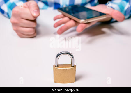 Geschlossenen Vorhängeschloss, im Hintergrund ein Mann mit einem Telefon umgekippt. Das Konzept der Sichern des Telefons, Cyber Attack, Datensicherheit, Probleme auf eine persönliche Stockfoto