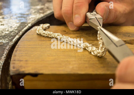 Silber Schmuck Handwerk mit Männer Hände halten Werkzeuge in den Vordergrund Stockfoto