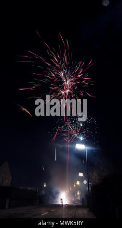 Foto von einem Feuerwerk werden lassen, die bis in den Himmel und explodiert in roten und grünen Farben und kann man auch den Mond sehen "schwebt" über Stockfoto