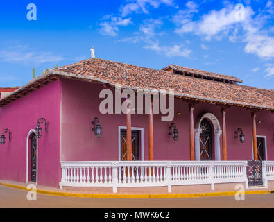 GRANADA, Nicaragua, Mai 14, 2018: Outdoor Ansicht der Fassade Gebäude mit rosa Wand, Tür und Dach in einem wunderschönen blauen Himmel Hintergrund im historischen Zentrum von Granada Stockfoto