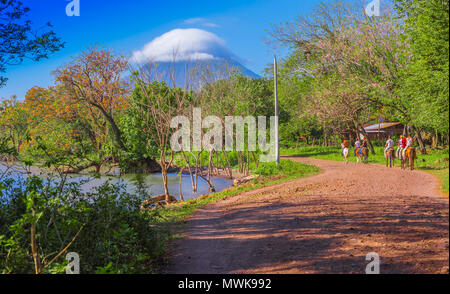 OMETEPE, Nicaragua, Mai, 14, 2018: Nicht identifizierte Personen ein Pferd Reiten in einem schweren Ökosystem mit einer goregous Blick auf Vulkan Concepcion im Horizont, in der Nähe von einem See in Isla Ometepe Stockfoto