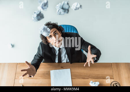 Portrait von betonte Unternehmer werfen zerknittertes Papier beim Sitzen am Arbeitsplatz im Büro Stockfoto