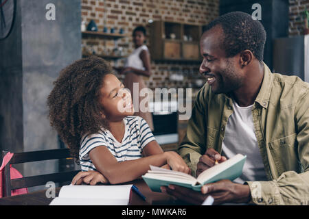 Vater und Tochter zusammen ein Buch lesen am Küchentisch Stockfoto