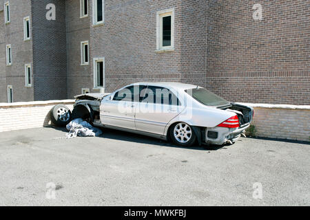 Eine ruinierte Farbe silber Auto auf einem Parkplatz vor einem Bürogebäude Stockfoto
