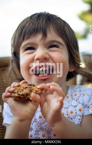 Ein 16-Monate altes Mädchen heraus lachen, wenn Sie ein Cookie isst. Stockfoto