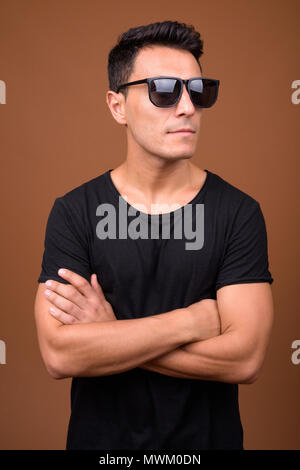 Junge schöne Hispanic Mann gegen braunen Hintergrund Stockfoto