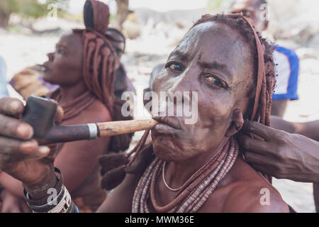 NAMIBE/ANGOLA - 28 Sep 2013 - Portrait der Afrikanischen ältere Frau, die zu einem Stamm mit Pfeife rauchen. Stockfoto