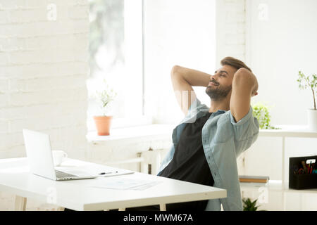 Lächelnd entspannte Arbeiter lehnte sich zurück in den Stuhl während der Arbeit Pause Stockfoto