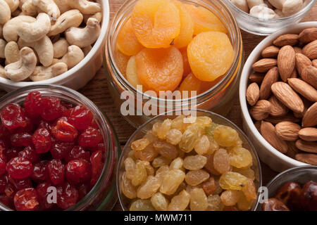 Nüsse und getrocknete Früchte Sortiment getrocknete Aprikosen, getrocknet, Kirschen, Rosinen, Mandeln, Cashews, Datum, Früchte, Erdnüsse auf hölzernen Tisch. Ansicht von oben. Stockfoto