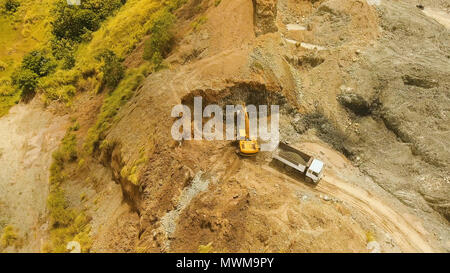 Bagger lädt die Lkw im Steinbruch. Luftaufnahme Radlader bagger Maschine laden Muldenkipper im Steinbruch. Earth mover laden Muldenkipper mit Felsen im Steinbruch. Philippinen. Travel Concept. Stockfoto