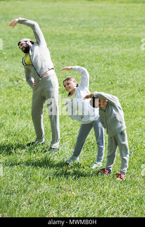 Gerne sportliche Familie tun, körperliche Bewegung auf Gras Stockfoto