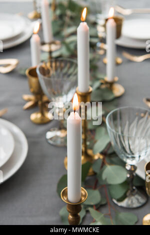 Selektiver Fokus der rustikalen Tisch mit Eukalyptus, altmodisch, Besteck, Kerzen, Kerzenhalter und leere Teller Stockfoto