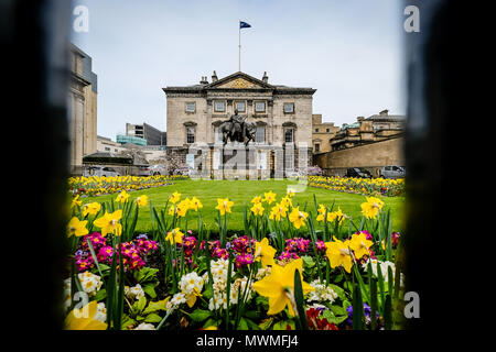 Edinburgh, Schottland - April 27, 2017: Royal Bank of Scotland durch den Zaun gesehen, mit Blumengarten im Vordergrund an einem bewölkten Tag. Stockfoto