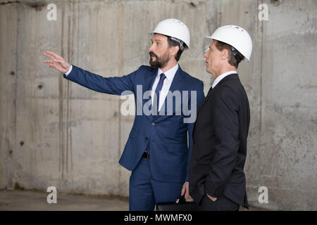 Zwei professionelle Architekten in harte Hüte über Projekt- und weg schauen Stockfoto