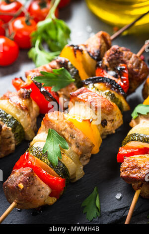 Gegrillte Shish Kebab oder Schaschlik mit Gemüse auf schwarzen Steintisch. Schweinefleisch. Grill Fleischgericht. Stockfoto