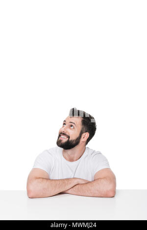 Schön lächelnden Mann sitzt am Tisch und Wegsehen auf Weiß isoliert Stockfoto