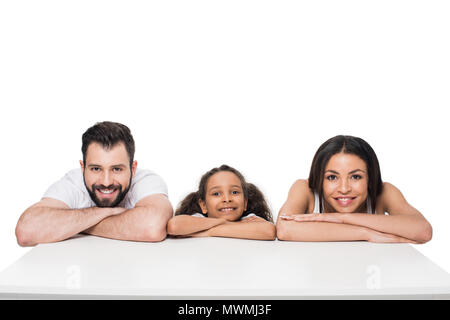 Happy multiethnischen Familie schiefen am weißen Tisch und lächelnd an Kamera Stockfoto