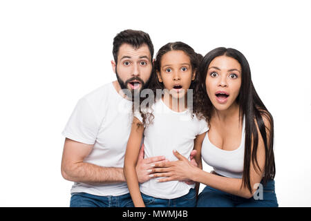 Überrascht multiethnischen Familie zusammen zu sitzen, und wenn man die Kamera isoliert auf weißem Stockfoto