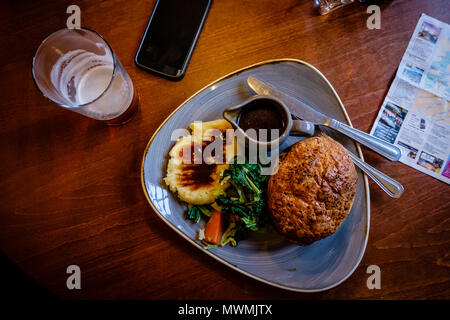 Blick von oben auf die traditionelle englische Beilage: Huhn und Mushroom pie mit Kartoffelpüree. Andere itens im Hinblick gehören Mobiltelefone und Bier. Edinbu Stockfoto