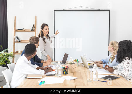 Jungen asiatischen Geschäftsfrau auf Leinwand während der Präsentation im Büro Stockfoto