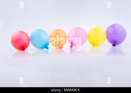 Bunte kleine Luftballons in Linie auf weißem Hintergrund Stockfoto