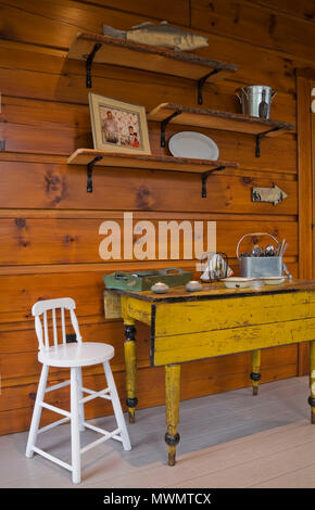 Kleine weiße Hochstuhl und alten gelben antiken Tisch mit Collectibles im Wintergarten in einem Cottage style flach Anmelden Profil und Holz home Stockfoto