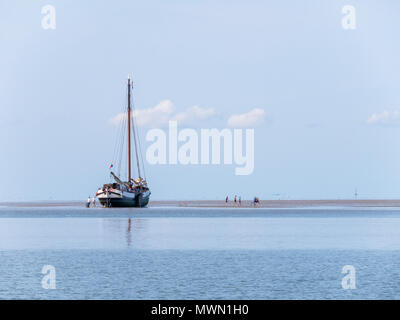 Gruppe von Jugendlichen spielen auf Sand, Flach und ausgetrocknet ist, flacher Boden Segelyacht bei Ebbe am Wattenmeer, Niederlande Stockfoto