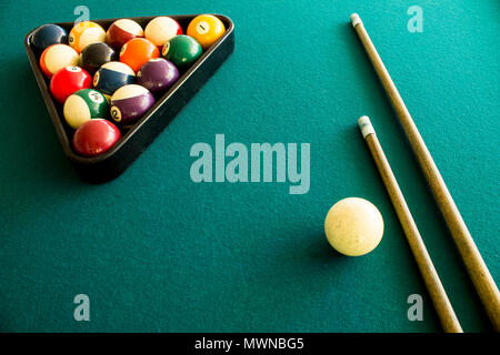 Kugeln in einem Dreieck auf einem grünen Tisch mit zwei cue Sticks angeordnet Stockfoto