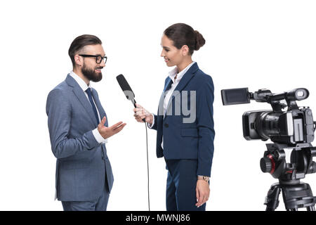 Lächelnd weibliche Journalistin mit Mikrofon und Videokamera interviewt Geschäftsmann, auf weissem isoliert Stockfoto