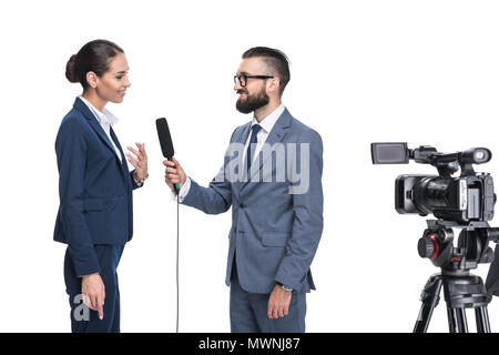 Männliche Journalist mit Mikrofon und Videokamera interviewt Geschäftsfrau, isoliert auf weißem Stockfoto
